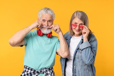 Photo of Senior couple in stylish outfits on orange background