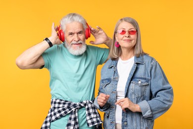 Photo of Senior couple in stylish outfits on orange background