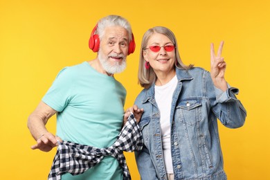 Photo of Senior couple in stylish outfits on orange background