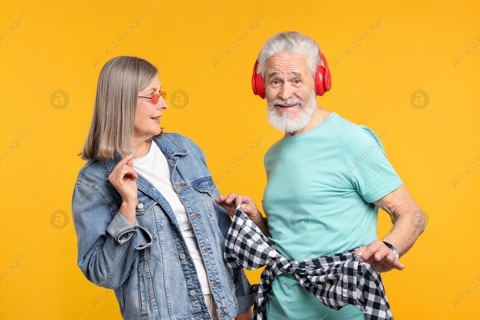 Senior couple in stylish outfits on orange background Photo of Senior couple in stylish outfits on orange background