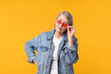 Photo of Senior woman wearing stylish sunglasses on orange background