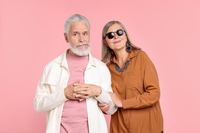 Photo of Senior couple in stylish outfits on pink background