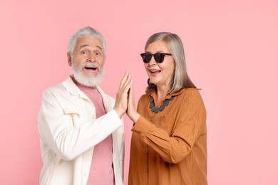 Photo of Senior couple in stylish outfits on pink background