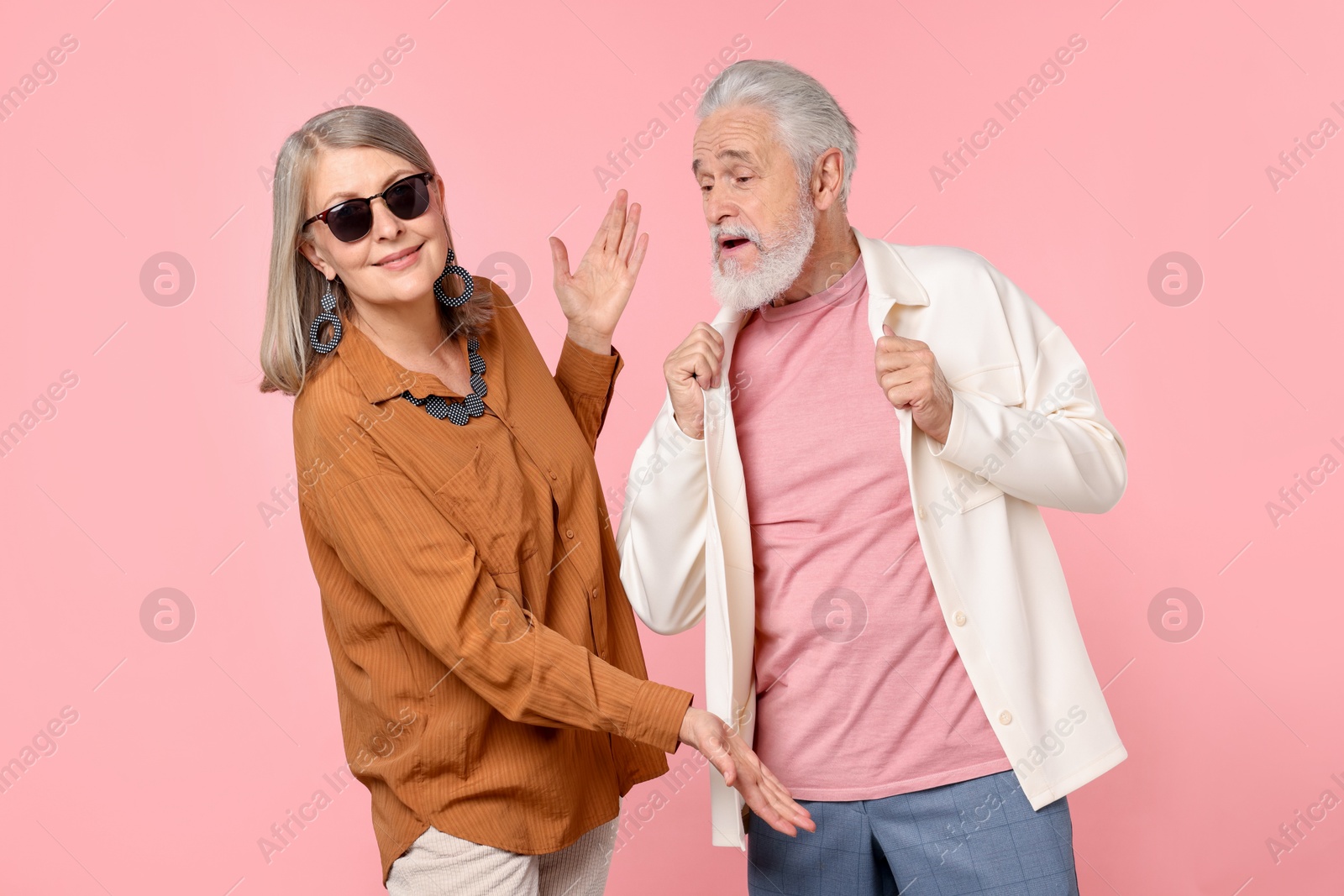 Senior couple in stylish outfits on pink background Photo of Senior couple in stylish outfits on pink background