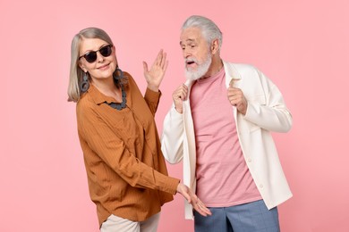 Photo of Senior couple in stylish outfits on pink background