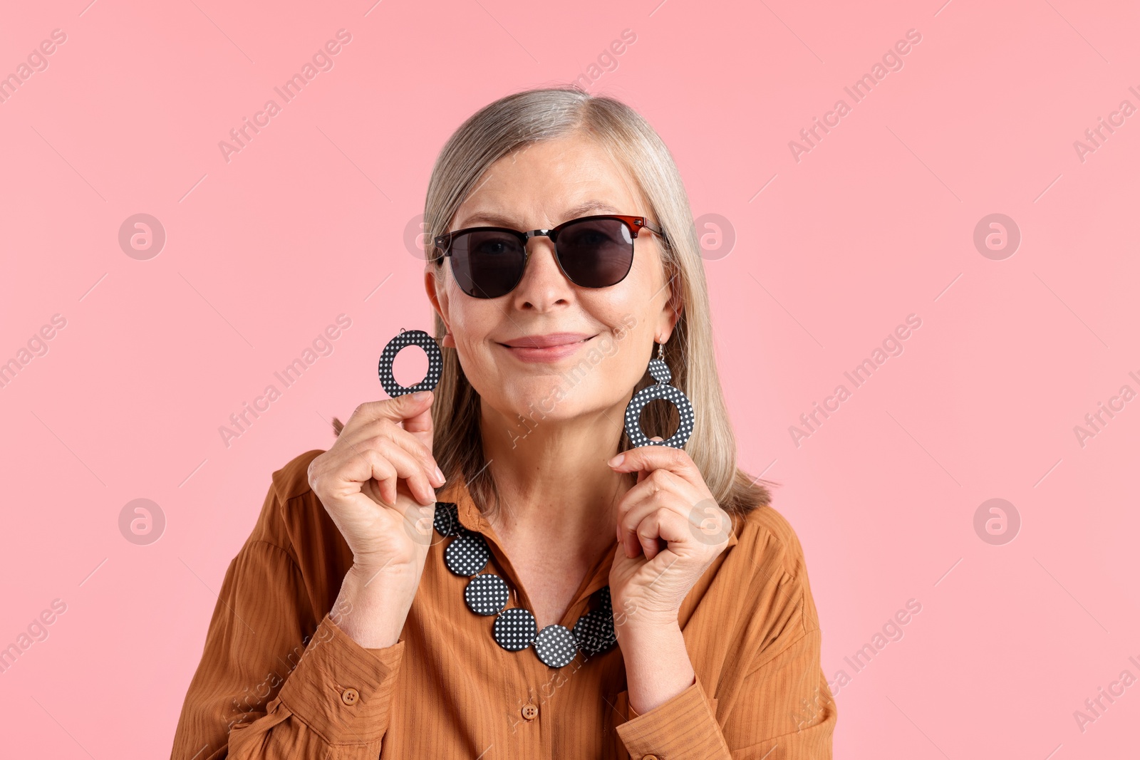 Senior woman in stylish outfit on pink background Photo of Senior woman in stylish outfit on pink background
