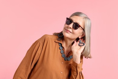 Photo of Senior woman in stylish outfit on pink background