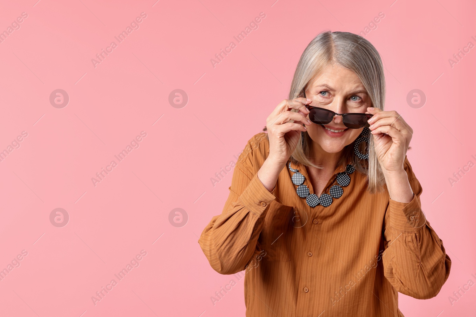 Senior woman in stylish outfit on pink background, space for text Photo of Senior woman in stylish outfit on pink background, space for text
