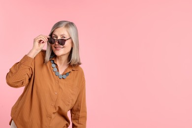 Photo of Senior woman in stylish outfit on pink background, space for text
