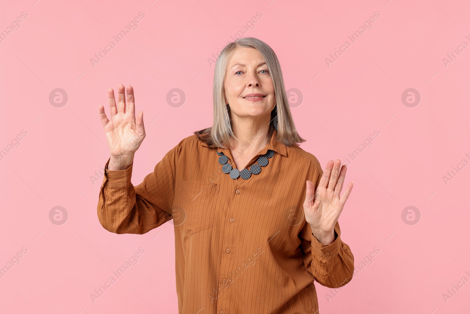 Senior woman in stylish outfit on pink background Photo of Senior woman in stylish outfit on pink background