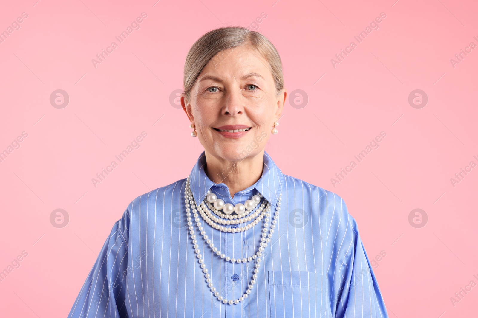Senior woman wearing elegant pearl jewelry on pink background Photo of Senior woman wearing elegant pearl jewelry on pink background
