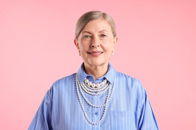 Photo of Senior woman wearing elegant pearl jewelry on pink background