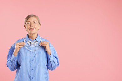Photo of Senior woman wearing elegant pearl jewelry on pink background, space for text