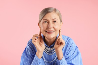 Photo of Senior woman wearing elegant pearl jewelry on pink background