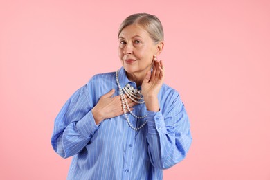 Photo of Senior woman wearing elegant pearl jewelry on pink background