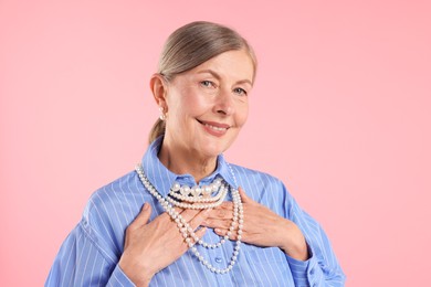 Photo of Senior woman wearing elegant pearl jewelry on pink background