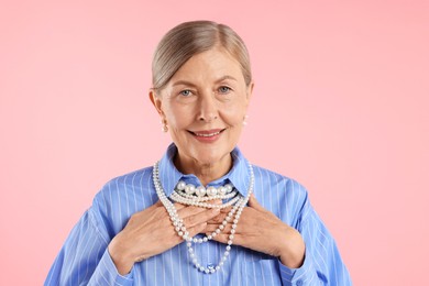 Photo of Senior woman wearing elegant pearl jewelry on pink background