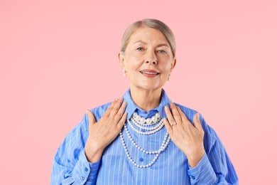 Photo of Senior woman wearing elegant pearl jewelry on pink background