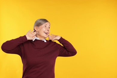 Photo of Happy senior woman in stylish outfit on orange background, space for text