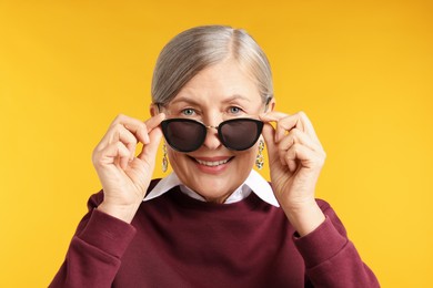 Photo of Happy senior woman in stylish outfit on orange background