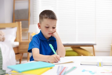 Photo of Dyslexia. Little boy writing at table indoors