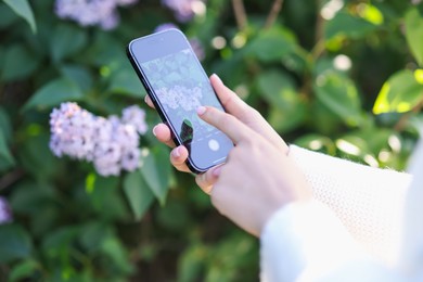 Photo of Woman using plant recognition application on smartphone outdoors, closeup