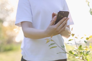 Photo of Woman using plant recognition application on smartphone outdoors, closeup