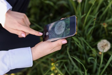 Photo of Woman using plant recognition application on smartphone outdoors, closeup
