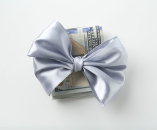 Photo of Money bonus. Dollar banknotes with bow isolated on white, top view