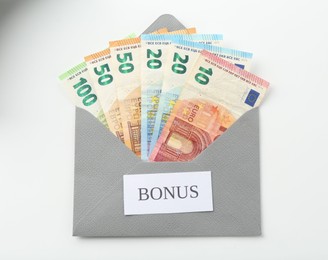 Photo of Envelope with word Bonus and euro banknotes isolated on white, top view