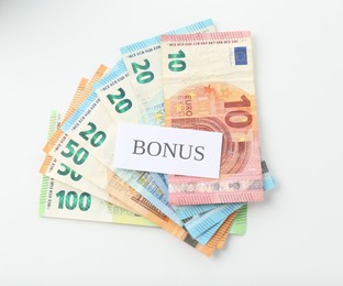 Photo of Euro banknotes and card with word Bonus isolated on white, top view