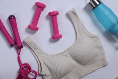 Photo of Sportswear, dumbbells, skipping rope and water bottle on white background, flat lay