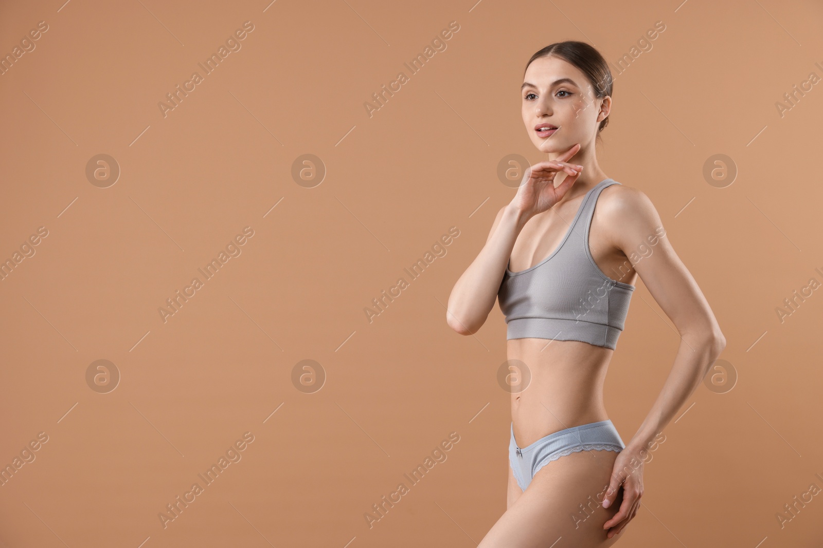Woman wearing beautiful underwear on dark beige background, space for text Photo of Woman wearing beautiful underwear on dark beige background, space for text