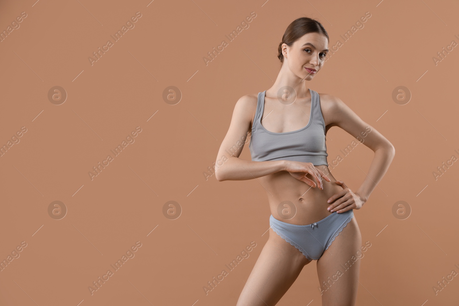 Woman wearing beautiful underwear on dark beige background, space for text Photo of Woman wearing beautiful underwear on dark beige background, space for text