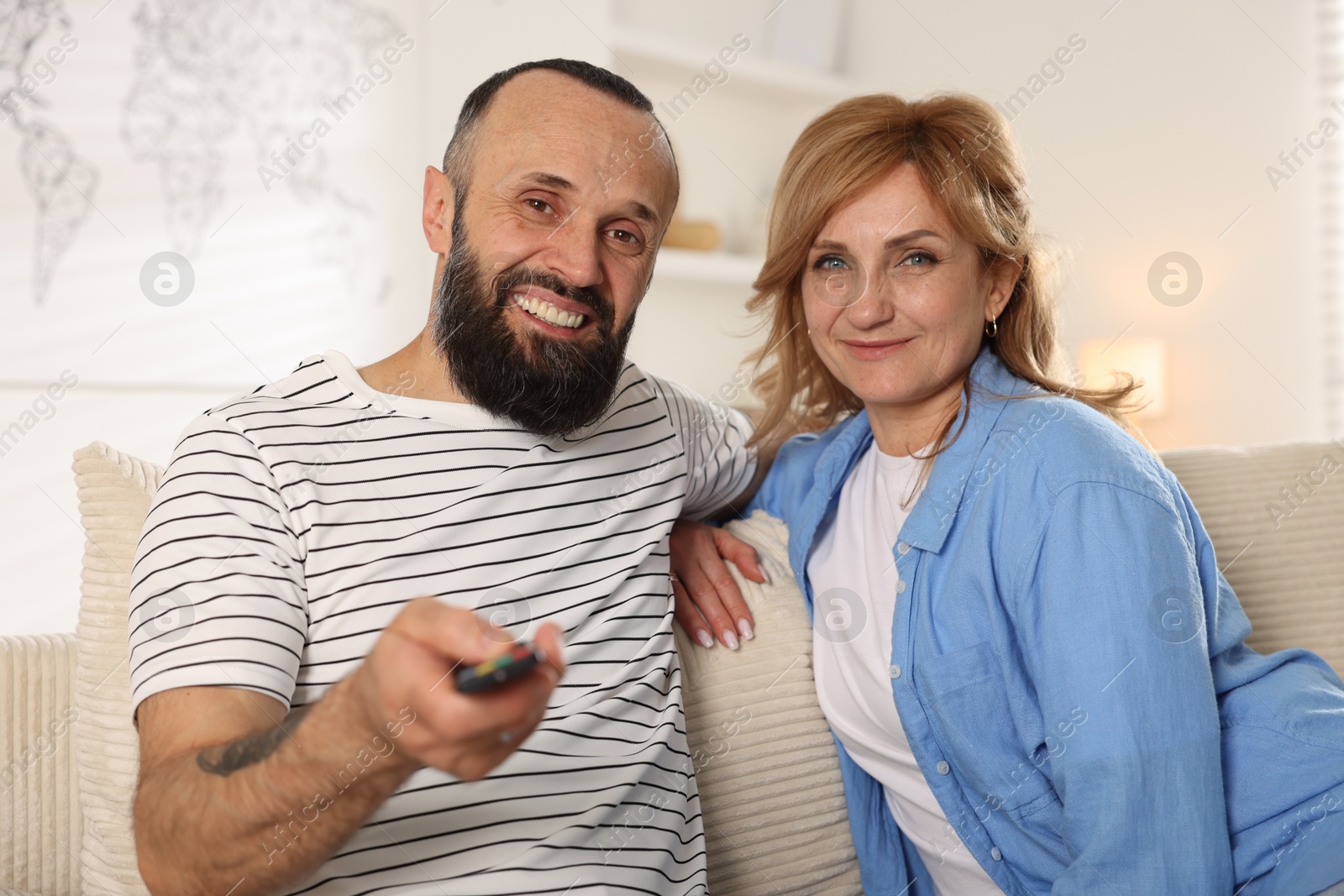 Lovely couple watching tv on sofa at home Photo of Lovely couple watching tv on sofa at home