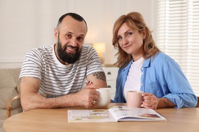 Photo of Lovely couple enjoying tea at wooden table indoors