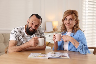 Photo of Lovely couple enjoying tea at wooden table indoors