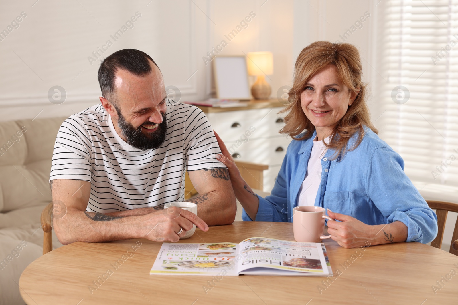 Lovely couple enjoying tea at wooden table indoors Photo of Lovely couple enjoying tea at wooden table indoors