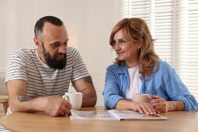 Photo of Lovely couple enjoying tea at wooden table indoors