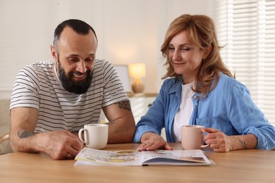 Photo of Lovely couple enjoying tea at wooden table indoors