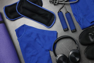 Photo of Sportswear, sneakers, skipping rope, headphones, ankle weights and fitness mat on grey background, flat lay