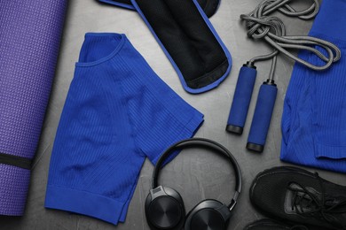 Photo of Sportswear, sneakers, skipping rope, headphones, ankle weights and fitness mat on grey background, flat lay