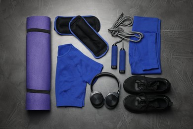 Photo of Sportswear, sneakers, skipping rope, headphones, ankle weights and fitness mat on grey background, flat lay