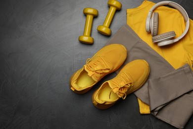 Photo of Sportswear, sneakers, dumbbells and headphones on grey background, flat lay. Space for text
