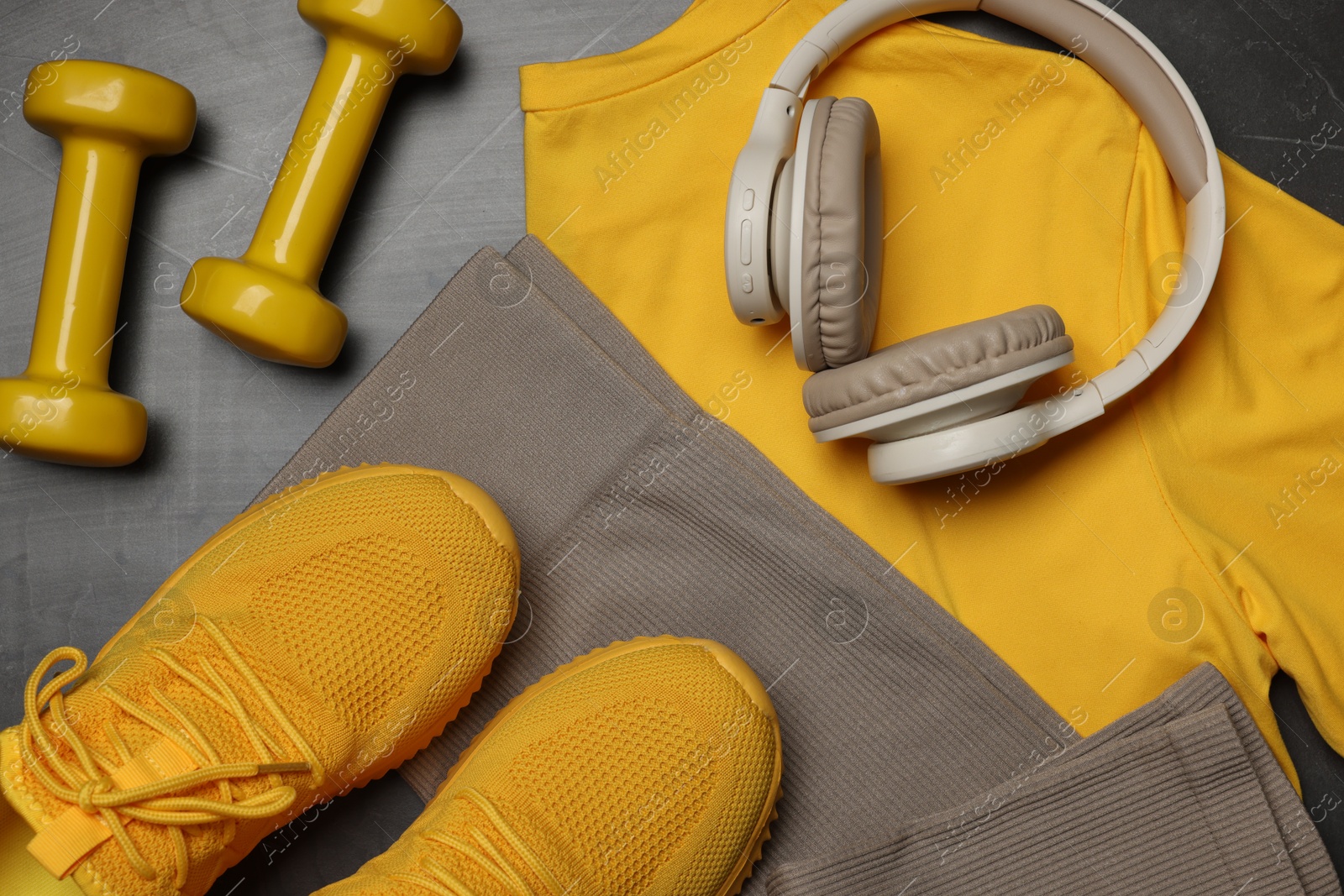 Sportswear, sneakers, dumbbells and headphones on grey background, flat lay Photo of Sportswear, sneakers, dumbbells and headphones on grey background, flat lay