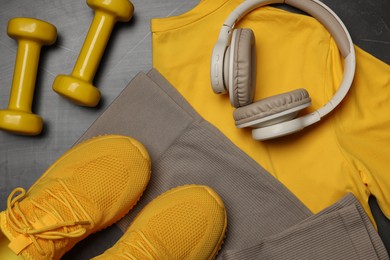 Photo of Sportswear, sneakers, dumbbells and headphones on grey background, flat lay