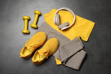 Photo of Sportswear, sneakers, dumbbells and headphones on grey background, flat lay