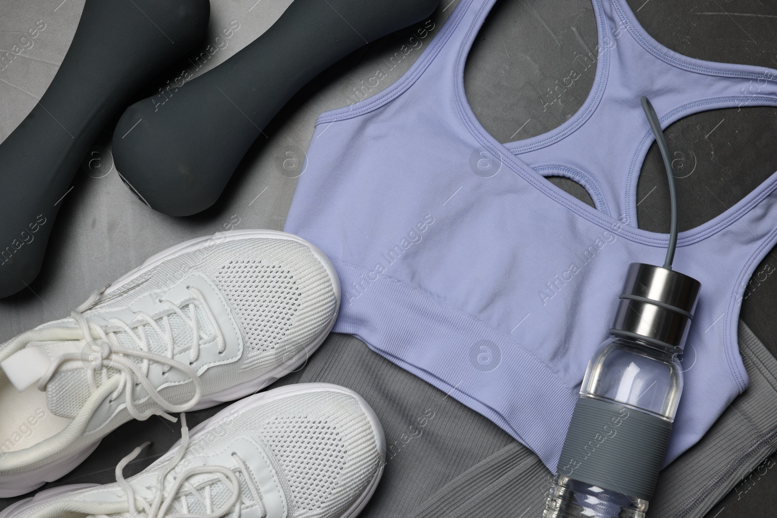 Sportswear, sneakers, dumbbells and water bottle on grey background, flat lay Photo of Sportswear, sneakers, dumbbells and water bottle on grey background, flat lay