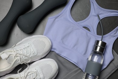 Photo of Sportswear, sneakers, dumbbells and water bottle on grey background, flat lay