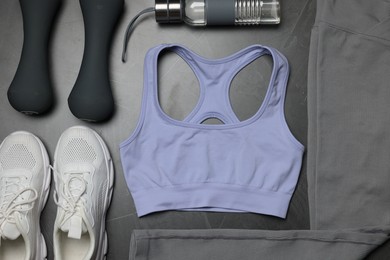 Photo of Sportswear, sneakers, dumbbells and water bottle on grey background, flat lay
